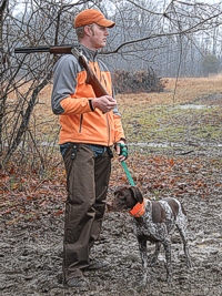 A young shorthair, already a Senior Hunter, waits in the mud with his handler before his first ever Master run.