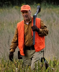 Pat wades through the grass back to the gunner's station, two pheasants on board. That shotgun over his shoulder is breached, which allows anyone in the field to see that it's safe.
